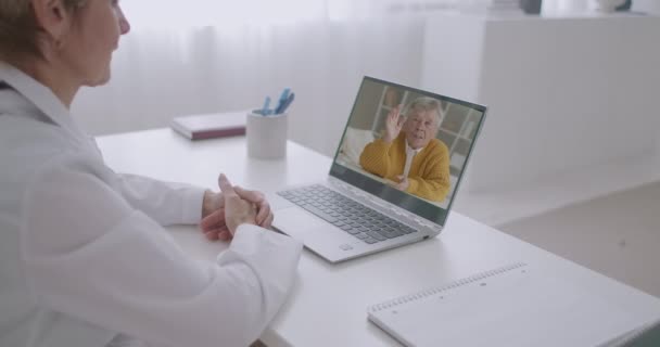 Patient âgé reste à la maison et appelle par caméra web à son médecin de famille, consultation par la santé, cardiologue et thérapeute femme l'écoute — Video