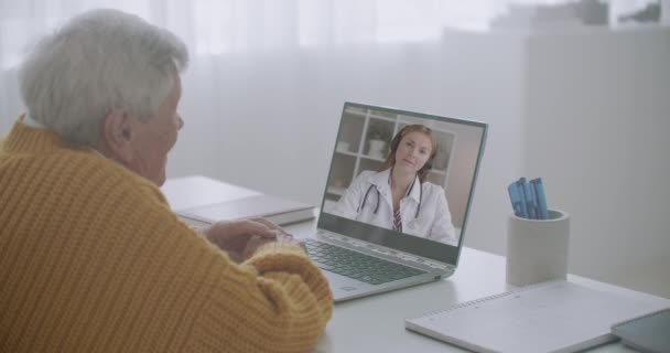 Idős beteg férfi hív video chat orvossal, fiatal női orvos válaszol neki, és konzultál — Stock videók