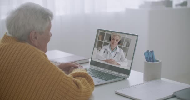Телесеанс по интернету для стариков и инвалидов, женщина разговаривает с пожилым мужчиной по видеосвязи — стоковое видео