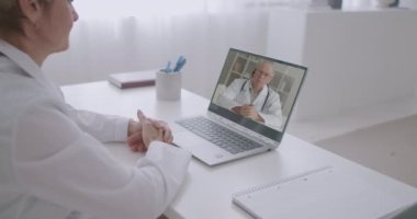 İki tıp doktoru, kendi kliniklerindeki dizüstü bilgisayarların web kameralarıyla video aracılığıyla iletişim kuruyor.