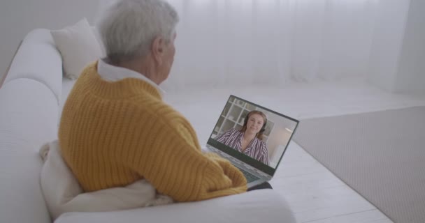Fiatal női szociális munkás hívja idős férfi videohívás, idősebb személy nézi őt a képernyőn, és hallgatja — Stock videók