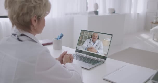 Online medische raad van twee ervaren beoefenaars, man en vrouw praten over ziekte en medicijnen — Stockvideo