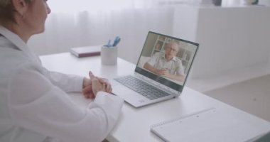 Hasta yaşlı adam doktorunu arıyor ve hastalığının belirtilerinden bahsediyor. Bilgisayarda görüntülü sohbet yapıyor. Kadın doktor onu dinliyor.