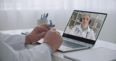 Tıp uzmanı internetten öğreniyor. Deneyimli tıp profesörünün konferansını dinliyor ve izliyor. Kadın doktor yüzü sergileniyor.