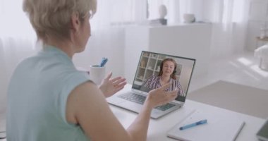 İki kadın internetten bilgisayarlarında görüntülü konuşma yapıyorlar, konuşuyorlar ve dedikodu yapıyorlar.