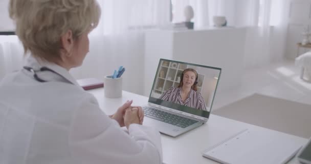 Žena lékař konzultuje on-line mladá žena pacienta, vzdálená komunikace s terapeutem na pandemii koronaviru — Stock video