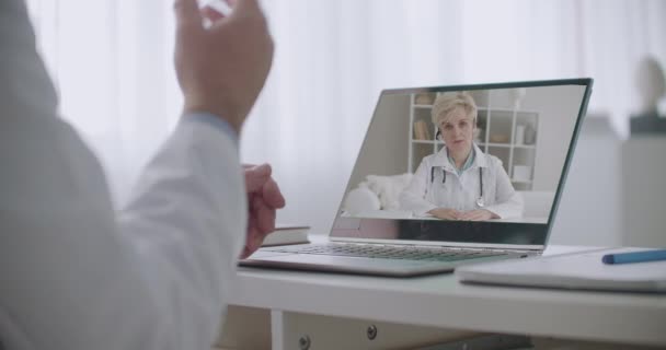 Donna medico sta tenendo conferenze sullo schermo del computer portatile, medico maschio sta discutendo con lei e gesticolando, primo piano delle mani — Video Stock
