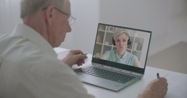 Online chat két ember, nő beszél, férfi nézi arcát a laptop kijelző és írás jegyzetek papírra — Stock videók