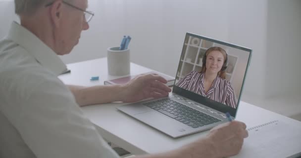 Jonge vrouw is het uitvoeren van training webinar, oude man is het bekijken van video op het scherm van zijn laptop thuis — Stockvideo