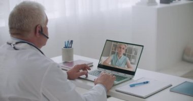 Kadın hasta video konusunda deneyimli bir tıp uzmanıyla görüşüyor. Adam web kameralı bir dizüstü bilgisayar kullanıyor.
