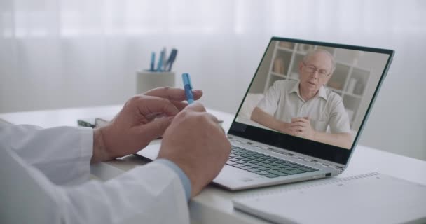 Yaşlı bir adam, doktorluk ofisinde dizüstü bilgisayarının ekranında, video kaset aracılığıyla psikoloğa danışıyor. — Stok video