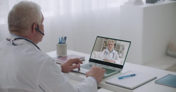 Två medicinska specialister chattar online med webbkamera, konsulterar och utbyter information — Stockvideo