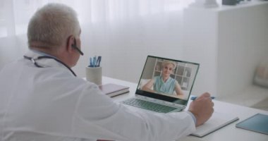 Doktor, yetişkin kadın hastaya internette danışmanlık yapıyor. Açıklıyor ve reçete yazıyor.