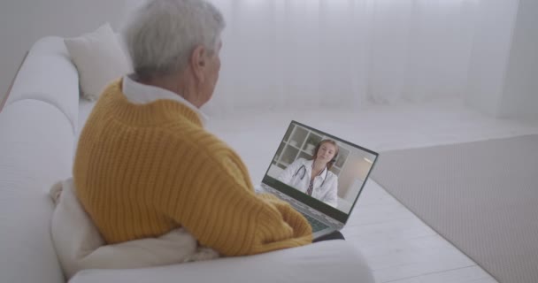 Női terapeuta hív videokonferencia az idős beteg férfi, ő nézi képernyőn laptop otthon marad — Stock videók