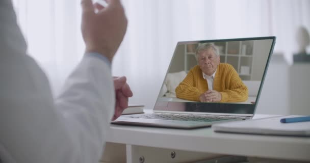 Kardiyolog, yaşlı erkek hastalara internet üzerinden danışmanlık yapıyor, tavsiyelerde bulunuyor ve iyileşme konusunda konuşuyor. — Stok video