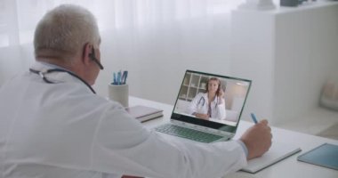 İki sağlık uzmanı video konferans hizmeti ile internet üzerinden iletişim kuruyor, genç kadın deneyimli meslektaşını dinliyor