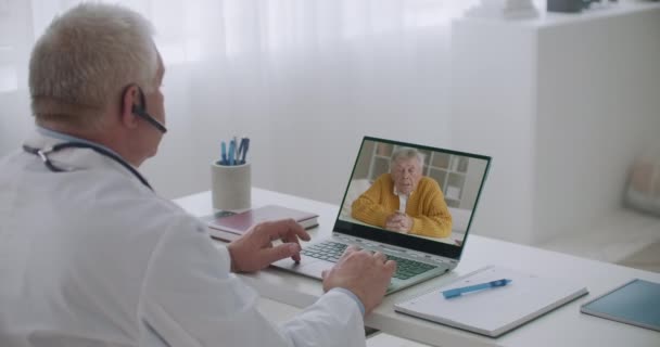 Urolog androlog konzultuje se starším pacientem on-line, muž mluví o symptomech a lékař poslouchá — Stock video