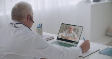 Profesyonel erkek terapist hastanın şikayetlerini videoyla dinliyor. Ofisteki hastalara danışmanlık yapıyor.