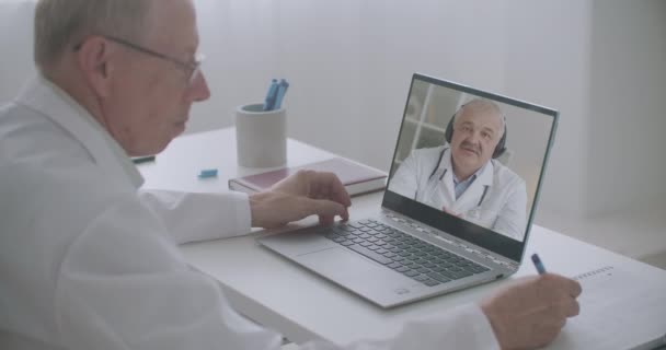 2人のウイルス学者と感染症学者がコロナウイルスのパンデミックについて話し合いノートパソコンのウェブカメラで話をしています — ストック動画