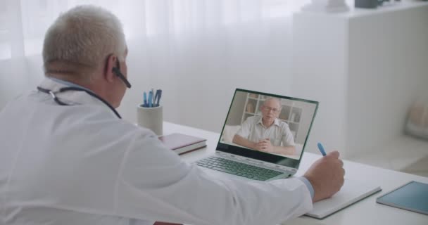 Profesionální mužský terapeut poslouchá stížnosti pacienta videohovory, konzultuje nemocné lidi online v kanceláři — Stock video