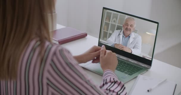 Pasien perempuan memanggil dokter melalui panggilan video melalui laptop dan berkonsultasi tentang penyakit online, laki-laki menjelaskan, wajahnya dipajang — Stok Video
