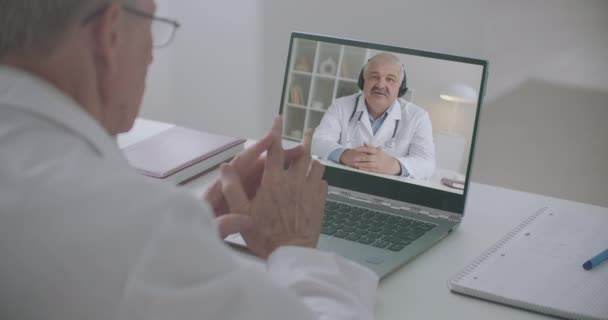 Terapeuta y cirujano se comunican y consultan por videoconferencia en línea en el portátil — Vídeo de stock