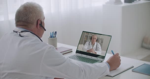 Överläkare på kliniken genomför online konferens med läkare på sjukhuset på morgonen, är manlig terapeut listenig — Stockvideo