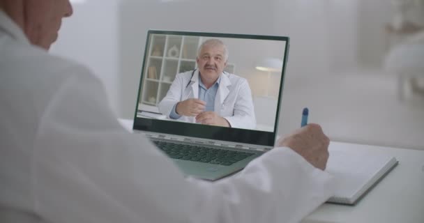 Dos médicos masculinos se comunican en línea por cámara web de notebook, aprendizaje y consultoría de profesionales de la salud — Vídeo de stock