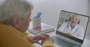 Yaşlı bir adam, yaşlılara yönelik teletıp danışmanlığı ve dizüstü bilgisayarla çevrimiçi video görüşmesi yoluyla kardiyologla görüşüyor.