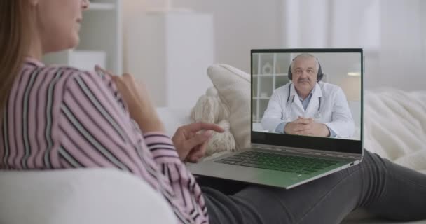 Videochat de médico y paciente, consulta en línea sobre salud y tratamientos, la mujer se queda en casa y habla con el médico masculino — Vídeos de Stock