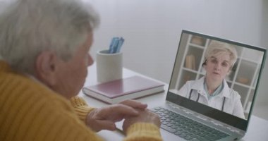 Yaşlı bir adam dizüstü bilgisayarında tıp profesörü Webinar 'ı izliyor. Kadın terapistin tavsiyelerini dinliyor.
