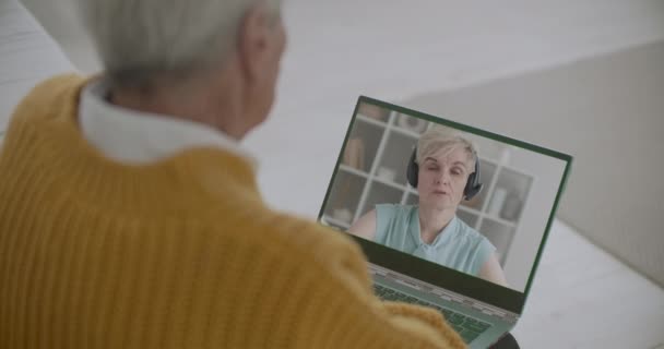 Vrouw van middelbare leeftijd is chatten door middel van video gesprek met haar oude vader, man zit thuis en het bekijken van dochter op het scherm van notebook — Stockvideo