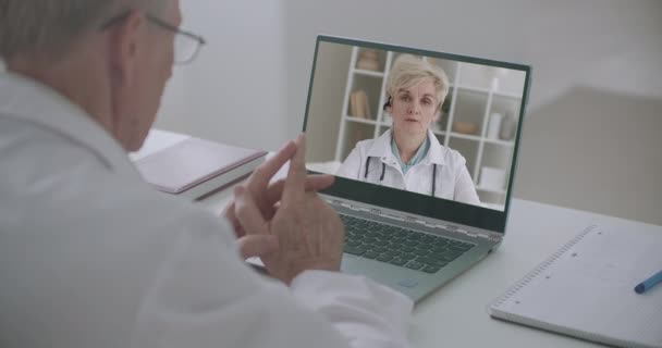 Terapeutas hombres y mujeres están comunicando y discutiendo los problemas de la medicina moderna por conferencia en línea, utilizando el ordenador portátil — Vídeo de stock