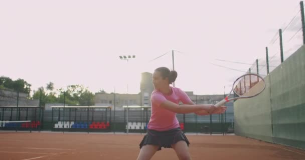 Seitenansicht einer jungen kaukasischen Frau, die auf einem Tennisplatz Tennis spielt und einen Ball in Zeitlupe zurückgibt — Stockvideo