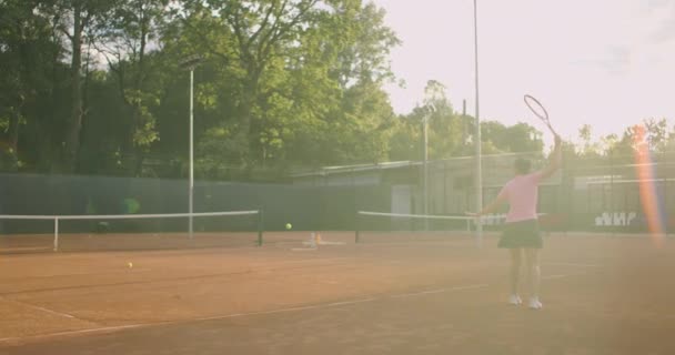 Zmęczona brunetka tenisistka spaceruje po korcie tenisowym, dochodząc do siebie i koncentrując się. Przerwa w meczu tenisowym. Tenisista po meczu na mapie o zachodzie słońca w zwolnionym tempie. — Wideo stockowe