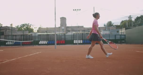 Привабливий спортсмен Позиціонує поблизу мережі в тенісному корті. Молода атлетична жінка грає в теніс, ходить в критий корт, жінка-програвач стає на ігрову позицію, навчальний день — стокове відео