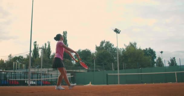 Zpomalený film: Mladá kavkazská teenager ženský tenista sloužící během hry nebo praxe. Tenista sloužící na hliněném kurtu. — Stock video