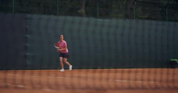 Επαγγελματική εξοπλισμένη γυναίκα χτυπάει σκληρά την μπάλα του τένις με ρακέτα τένις. Γυναίκα τενίστρια σε δράση κατά τη διάρκεια του παιχνιδιού. Φοράει μη επώνυμα αθλητικά ρούχα.. — Αρχείο Βίντεο
