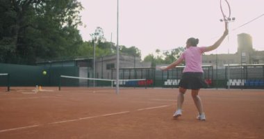  Sahada tenis oynayan beyaz bir kadın ağır çekimde topu geri getiriyor.