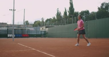  Sahada tenis oynayan beyaz bir kadın ağır çekimde topu geri getiriyor.
