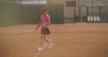 Yorgun esmer bir bayan tenisçi tenis kortu boyunca iyileşme ve konsantrasyon içinde yürüyor. Tenis maçında mola. Günbatımında haritadaki maçtan sonra yavaş çekimde tenis oyuncusu.
