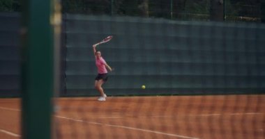 Genç bir kadın tenis kortunda raketle yürüyor. Mavi gömlekli ve siyah şortlu çekici esmer kadın tenis kortuna giriyor. Kopyalama alanı ile tam uzunluk takip çekimi