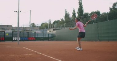  Sahada tenis oynayan beyaz bir kadın ağır çekimde topu geri getiriyor.