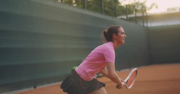 Profesionist echipat de sex feminin bate tare mingea de tenis cu racheta de tenis. Jucătoare de tenis în acțiune în timpul jocului. Ea poartă haine sport fără marcă . — Videoclip de stoc