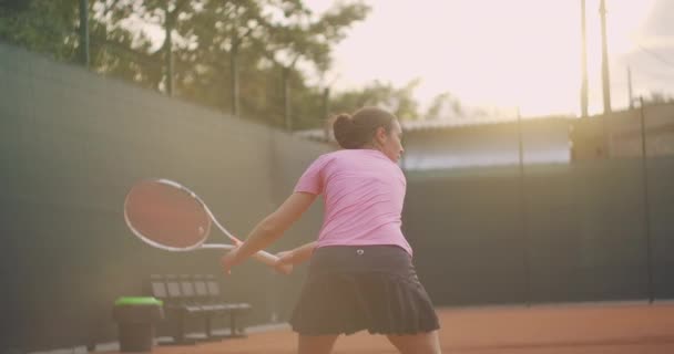 Profesional dilengkapi perempuan mengalahkan keras bola tenis dengan raket tenis. Pemain tenis wanita beraksi selama permainan. Dia mengenakan pakaian olahraga tanpa merek. — Stok Video