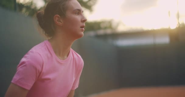Slow Motion kommersiella bilder av tennis praxis genom tennisbana nätet. Rak utsikt över en kvinnlig idrottsman som spelar tennis spel. En tonårsidrottsman slår bollen under idrottsträning — Stockvideo