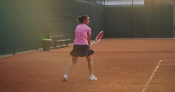 Profesional dilengkapi perempuan mengalahkan keras bola tenis dengan raket tenis. Pemain tenis wanita beraksi selama permainan. Dia mengenakan pakaian olahraga tanpa merek. — Stok Video