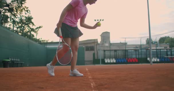 Vista de baixo ângulo em câmera lenta de uma jovem tenista preparando-se para servir uma partida de tênis. Uma mulher atleta é poderosamente bater uma bola durante a prática esportiva. Imagens de uso comercial — Vídeo de Stock