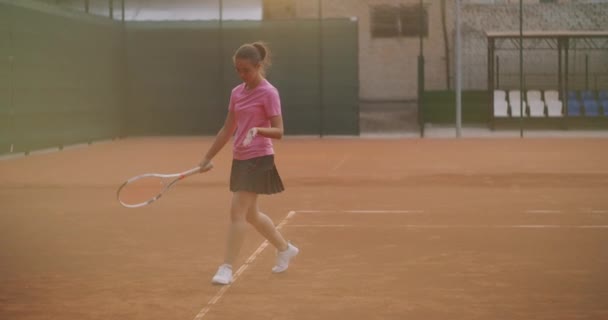 En trött brunett kvinnlig tennisspelare går längs tennisbanan återhämta sig och koncentrera sig. Bryt en tennismatch. Tennisspelare efter matchen på kartan vid solnedgången i slow motion. — Stockvideo