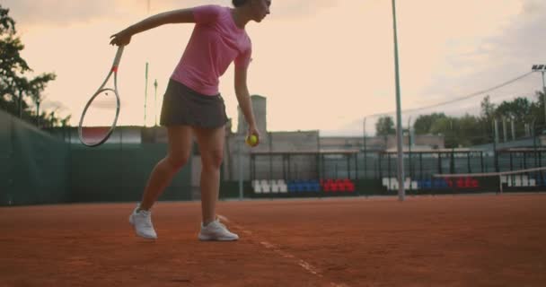 Slow motion: Young Caucasian teenager female tennis player serving during a game or practice. Tennis Player Serving On The Clay Court. — Stock Video